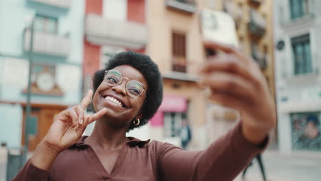 Pretty-female-vlogger-showing-peace-gesture-taking-photo-outdoors