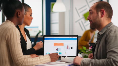 busy diverse employees analysing annual financial statistics sitting in front of laptop