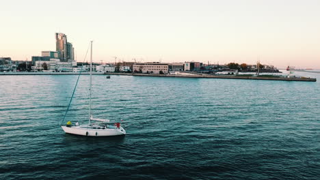 drone volando sobre un yate navegando hacia la bahía al atardecer