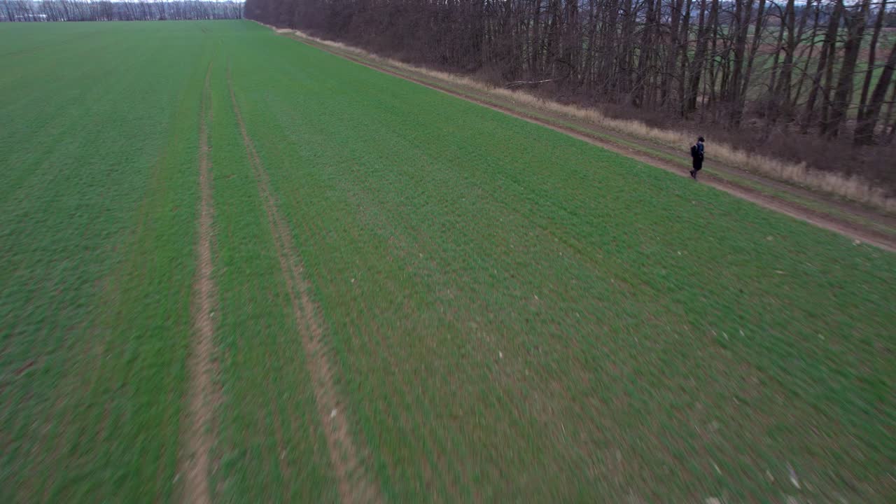 un agricultor caminando por el borde de un campo verde sembrado en una fría mañana de primavera