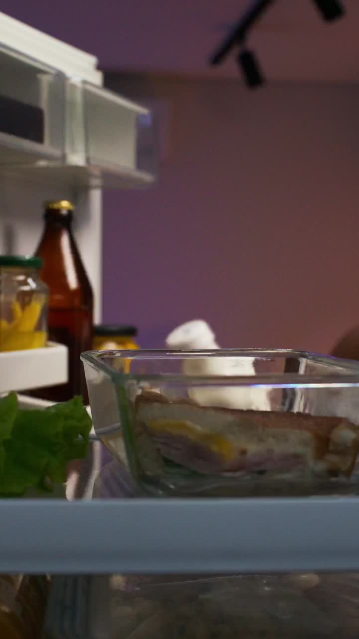 Person eating a sandwich from the refrigerator