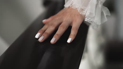 manicured hand of bride in wedding dress touches railing