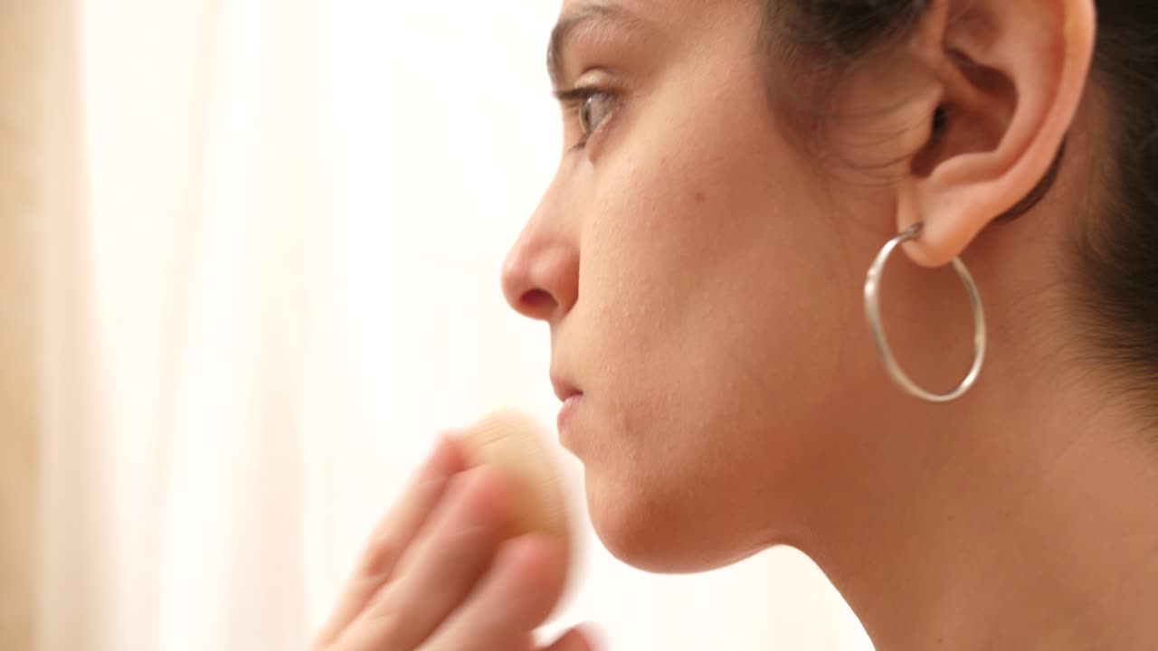 Giovane donna che applica il trucco sul viso con una spugnetta