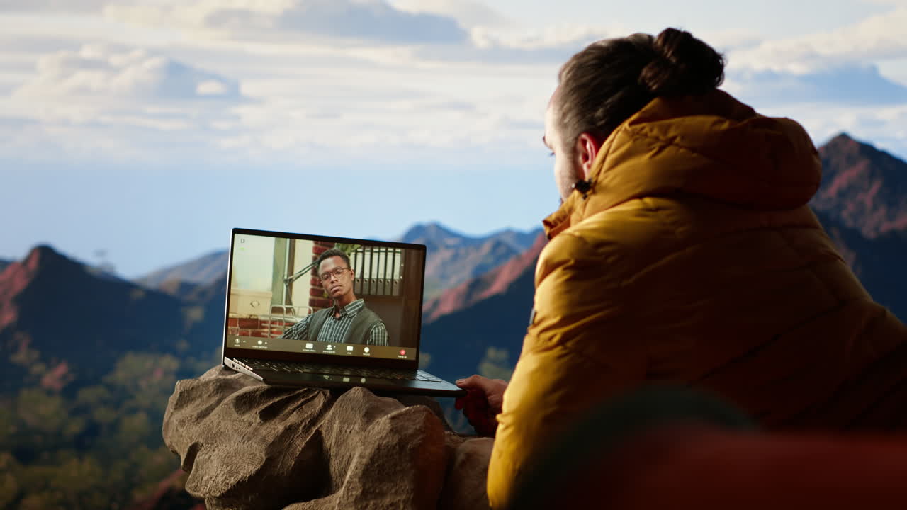 joven ceo entrando en una llamada de video desde la cima de la montaña con una señal fuerte