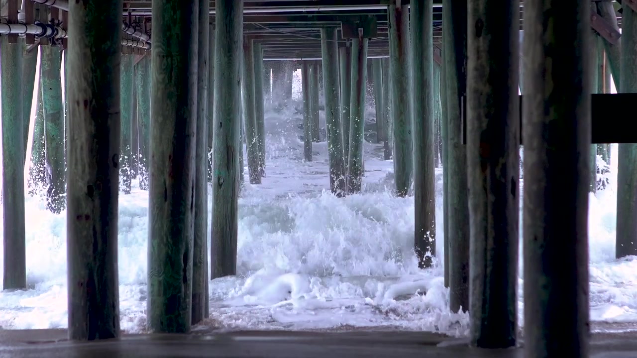 Waves crashing underneath a pier