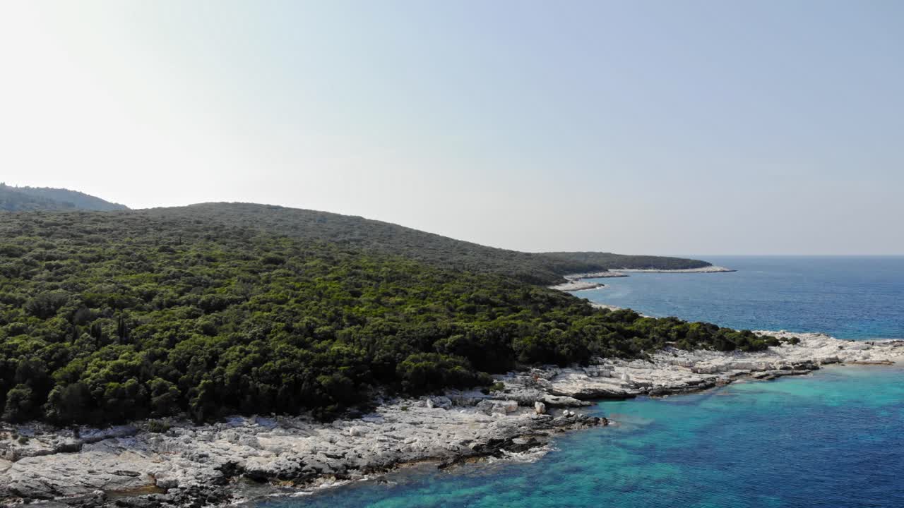 Pittoreschi pendii montani che incontrano le acque rocciose e ciottolose della spiaggia di Paralia Emplisi in Grecia durante il giorno - Ripresa aerea
