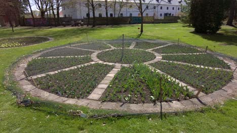 Moving-shots-of-a-garden-Olomouc-city,-botanic-garden-Flora-where-flowers-have-been-planted-in-one-place-and-a-large-white-house-in-the-distance