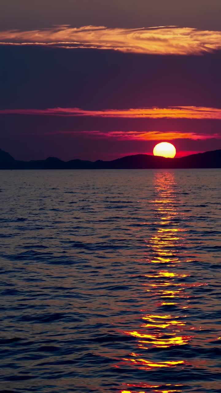 En fredfyldt solnedgang over havet med levende farver, fanget fra en lav engel, der skaber en rolig stemning