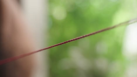 closeup of red string hanging in the air