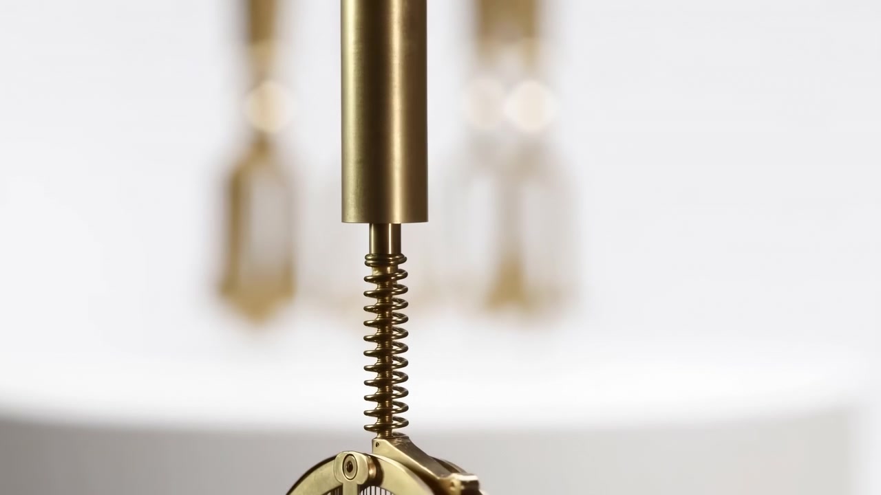 Abstract close view of blurred gold colored metal components suspended above a bright white curved surface, set against a clean minimal background with soft