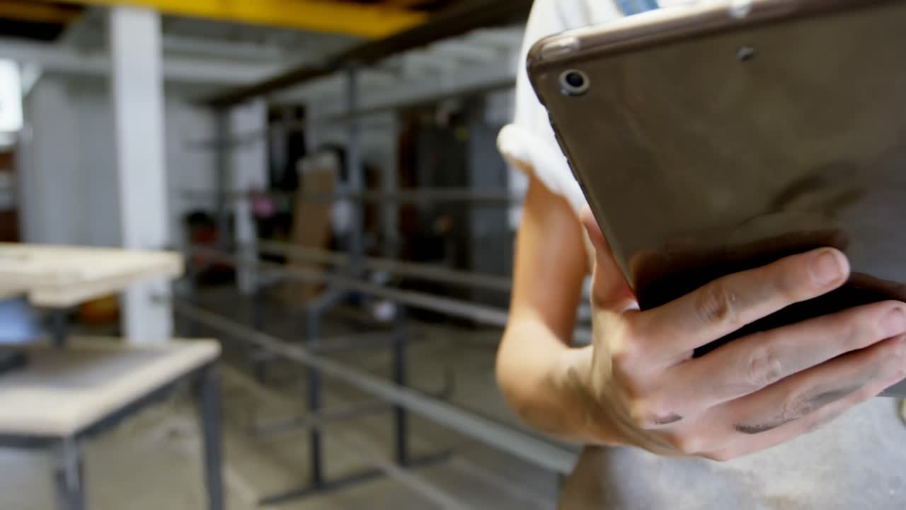 soldadora que utiliza una tableta digital en el taller 4k