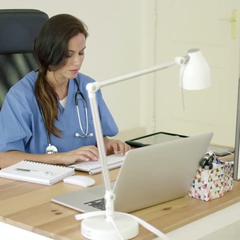 Young-female-doctor-sitting-typing-in-her-office