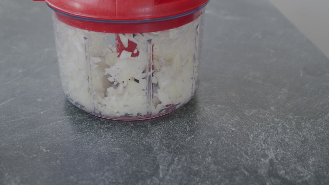 cortar cebollas blancas con un robot de cocina manual.