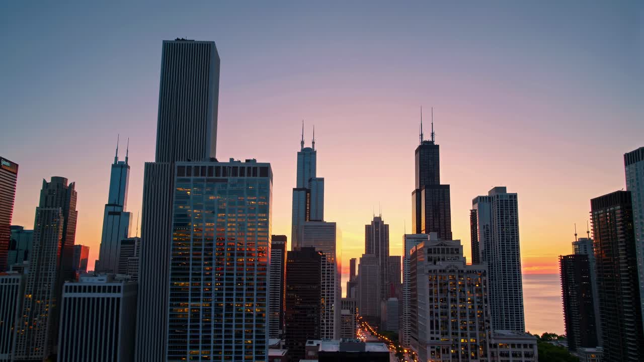 Aerial video captures a city skyline at sunset, showcasing tall skyscrapers against a colorful sky