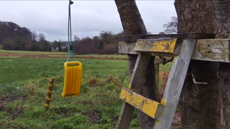 Un-Columpio-Roto-Se-Balancea-Con-El-Viento-Detrás-De-Un-Campo-Bajo-La-Lluvia