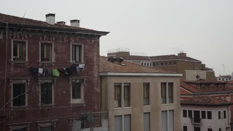 a clothesline full of drying laundry is visible on a classic venetian residential building, set against an urban backdrop.
