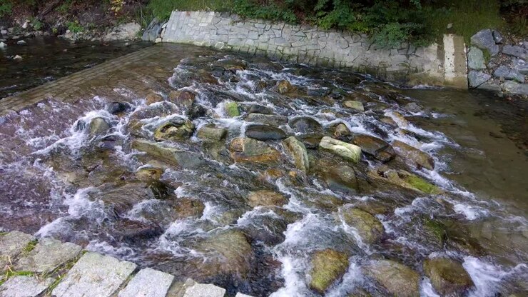 A static shot of a river flowing on the stone in the morning