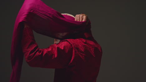 low key studio lighting shot of senior sikh man with beard tying fabric for turban against dark background 15