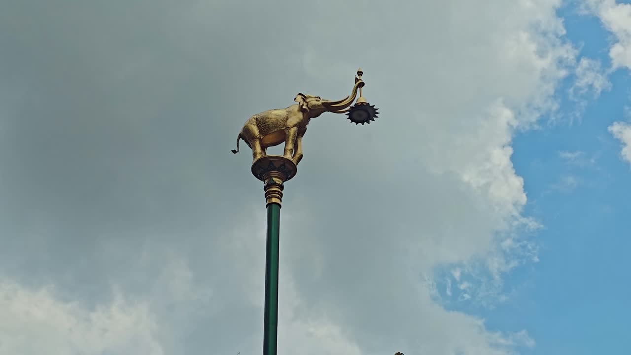 Statua di elefante dorato su lampione che sorregge una luce con la proboscide a Nakhon Nayok, Thailandia.