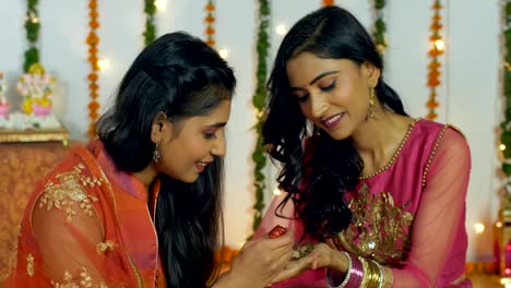 young girl applying beautiful mehndi design on the hands of her sister - diwali festival