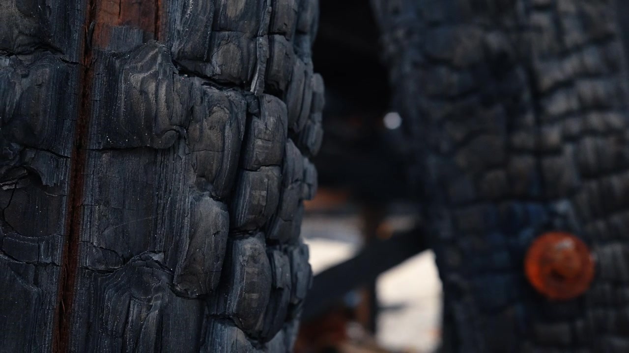 Dettagliata texture di legno nero carbonizzato dopo intensi danni da incendio. Primo piano estremo della superficie di legno bruciato che mostra motivi di carbone crepato e legno carbonizzato