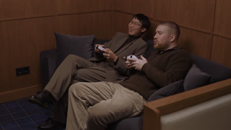 two men playing video games on a couch