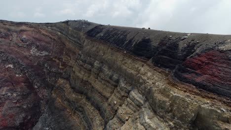 Flight-along-rock-strata-cliff-to-tourists-on-rim-of-Santa-Ana-Volcano