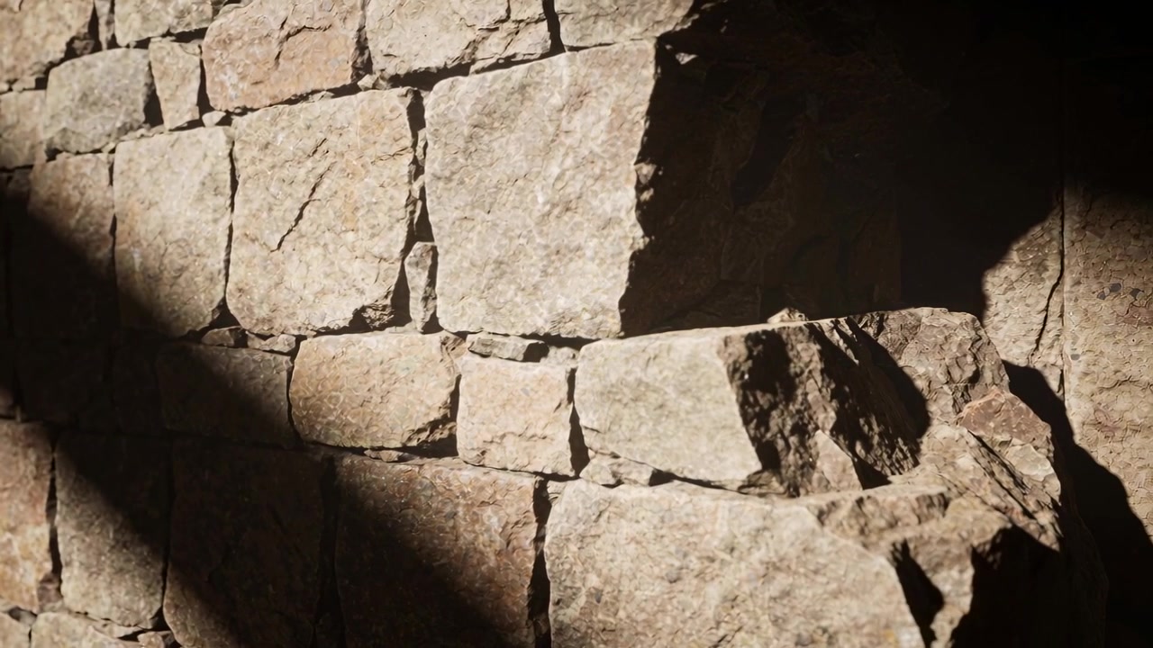 Sole che si sposta proietta una lunga ombra su un muro di pietra, rivelando una sporgenza e un incavo profondo, con spazio per il testo.