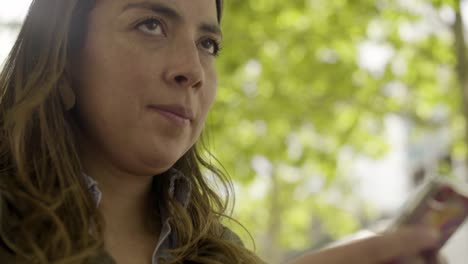 mujer joven concentrada enviando mensajes de texto en el teléfono inteligente.