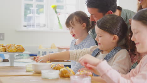 Familie-Mit-Down-Syndrom-Tochter-Backt-Und-Dekoriert-Kuchen-Und-Sitzt-Zu-Hause-Am-Tisch