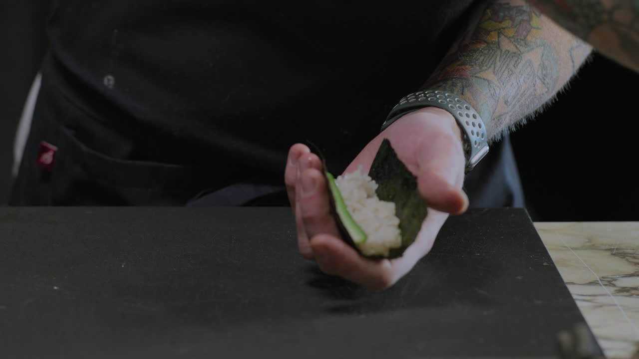 un primer plano de un chef preparando rollos de sushi