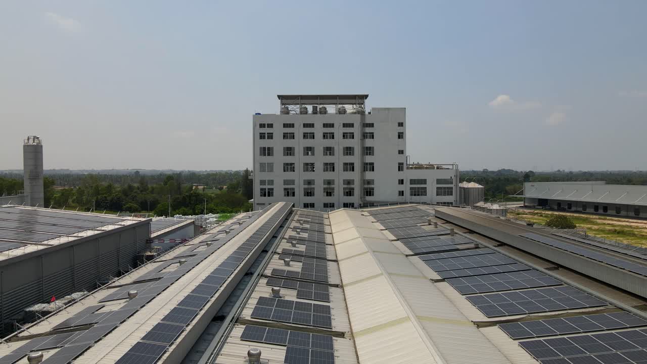 Solar panels on a building rooftop under clear skies, aerial view
