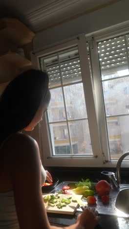 woman preparing a salad in a sunny kitchen