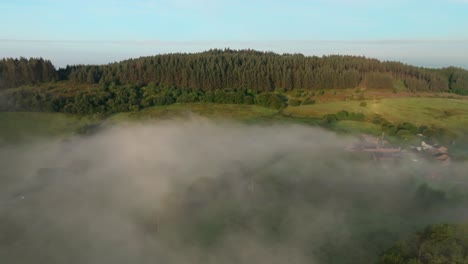 foggy landscape with camera flight towards forested hill at sunrise. beacon fell. summer. trough of bowland, lancashire, england, uk