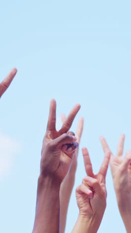 diverse hands showing peace signs against a blue sky