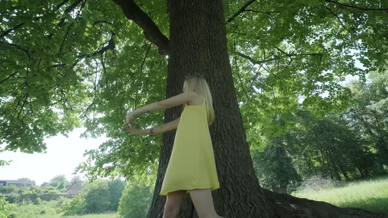 여름 공원에서 나무 에서 춤을 추는 노란색 드레스를 입은 여자