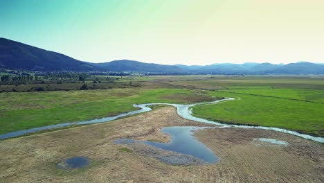 Weitwinkel-Dolly-In-Drohnenaufnahme-Des-Fließenden-Pfades-Des-Cerknica-Sees-Und-Der-Umliegenden-Hügel-Während-Des-Tages