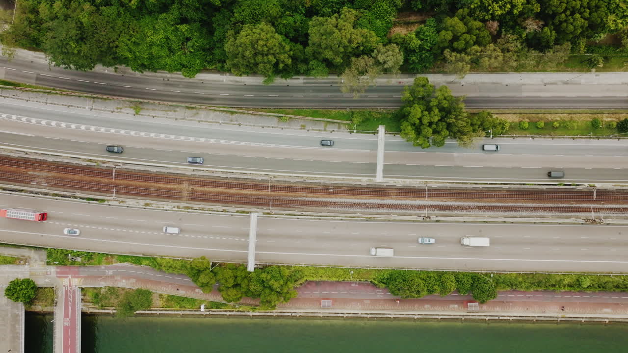 기차가 중앙을 지나가는 혼잡한 고속도로 바로 위를 패닝하는 드론 샷