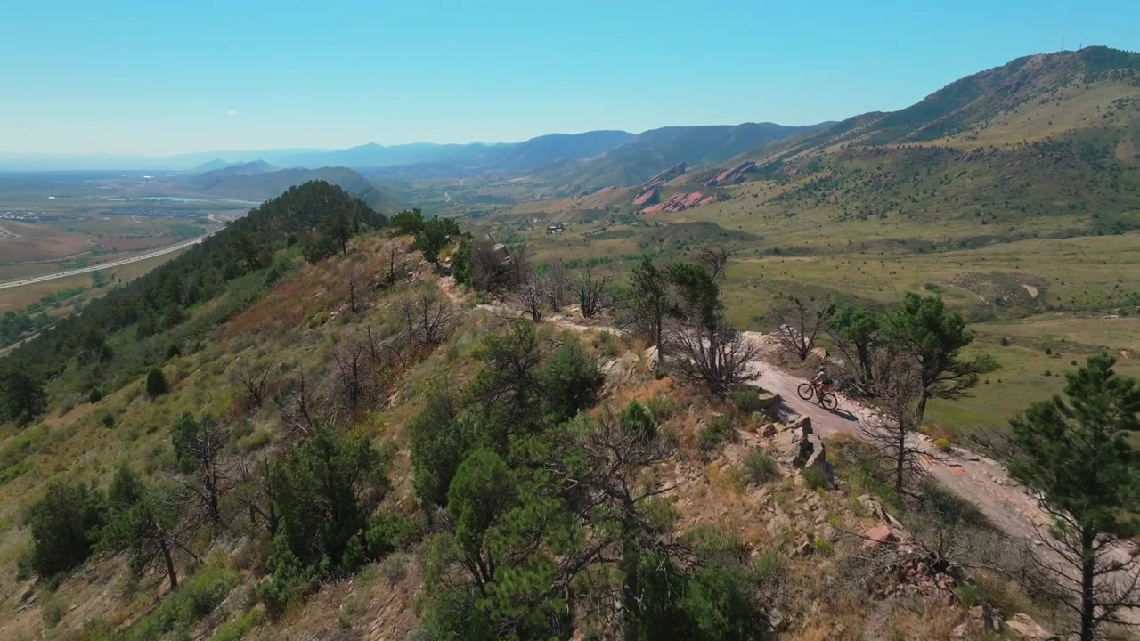 Ciclismo de Montanha. Esporte e fitness de bicicleta. Anfiteatro Red Rocks, Morrison, Golden, Colorado. Drone aéreo com efeito paralaxe na Trilha Dakota Ridge, sopés da Green Mountain em Denver, cordilheira frontal. Ciclista adulto em movimento de câmera para frente.