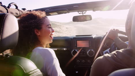 Young-couple-driving-with-sunroof-open,-rear-passenger-POV