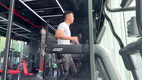 man running on a treadmill in a sleek gym setting with bright lighting and reflective surfaces