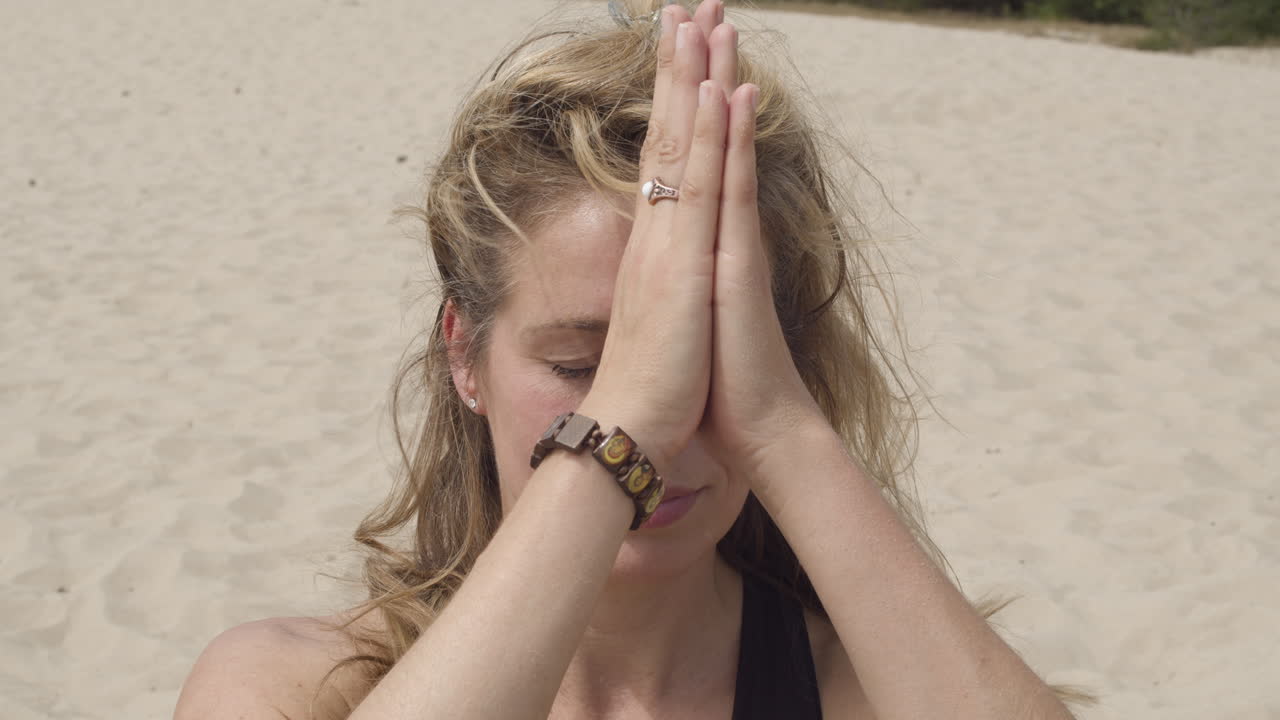접힌 손을 세 번째 눈 차크라로 가져오고 앞으로 구부리는 아름다운 여성 - 전면 보기를 닫습니다.