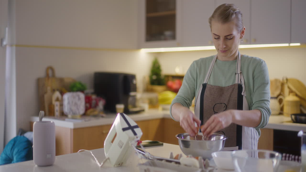 Nainen rikkoo raa'an kananmunan jauhoja sisältävään kulhoon ja valmistaa taikinaa leivontaan.