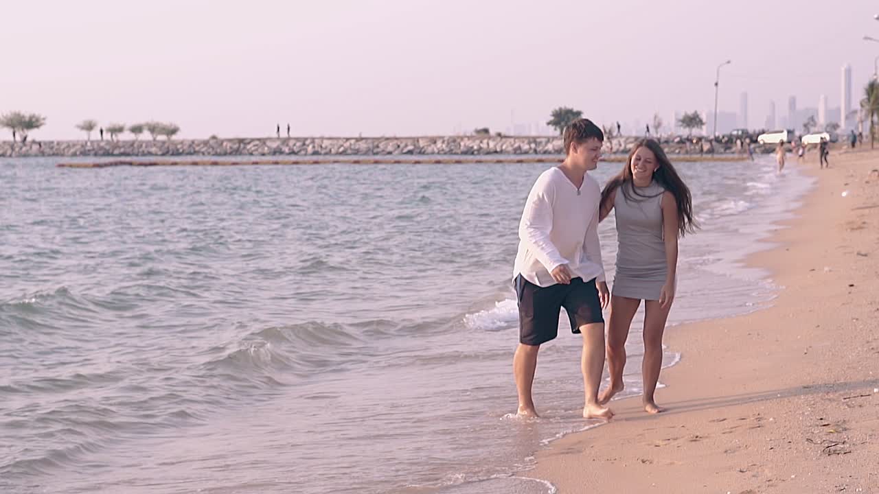 hermosa pareja besándose y caminando por la costa soleada en cámara lenta