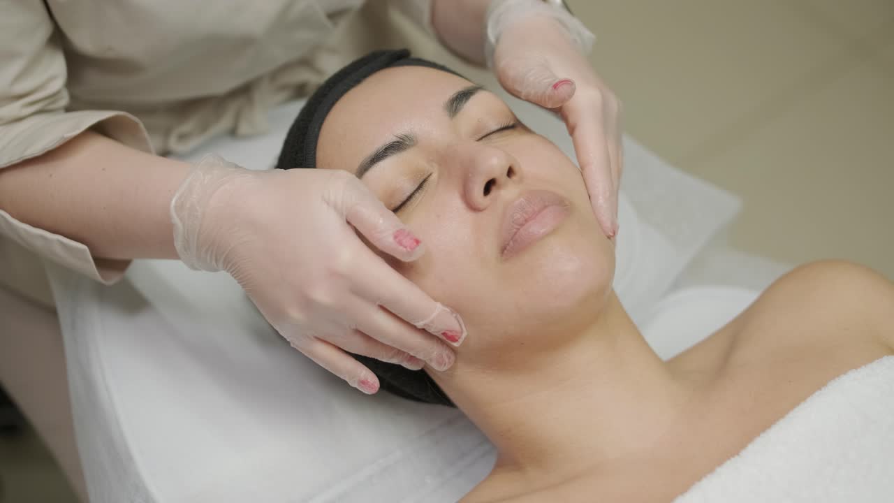 Mujer hermosa con máscara facial en el salón de belleza