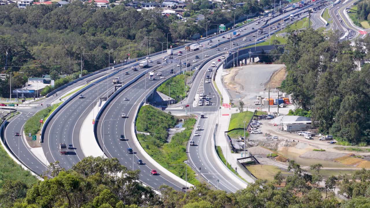 Drone footage captures vehicles on the M1 Highway, showcasing dynamic traffic flow amidst lush greenery and urban infrastructure