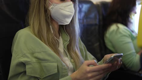 Mujer-En-El-Avión-Escucha-Música-Con-Auriculares-Usando-El-Teléfono-Móvil