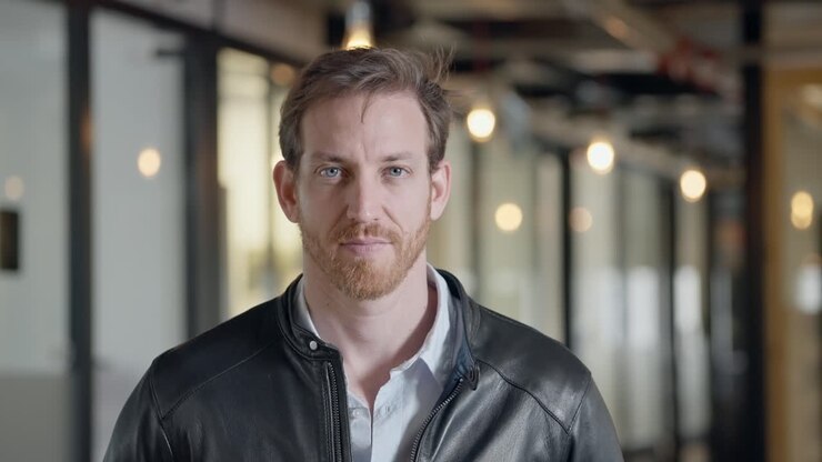 Portrait of a guy. Man in leather jacket staring directly into camera, exuding confidence, mystery, and intensity. Bold and stylish look with a hint of rebellion and intrigue. blue eyes caucasian.