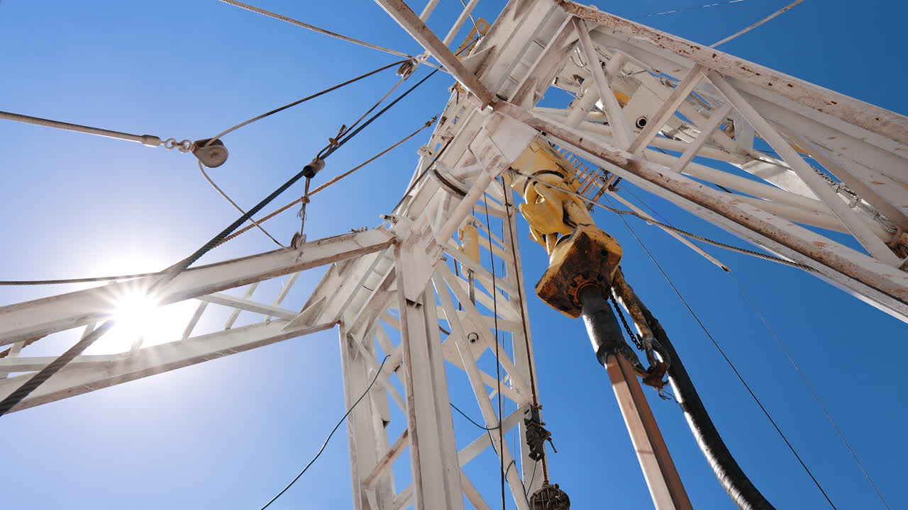 Boer is rotating drilling the ground to extract oil or gas. Low angle view at the equipment producing natural resources outdoors.