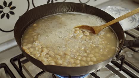 chickpeas boiling in hot water inside a cooking pan